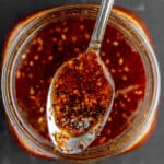 A spoon with salsa macha over a mason jar