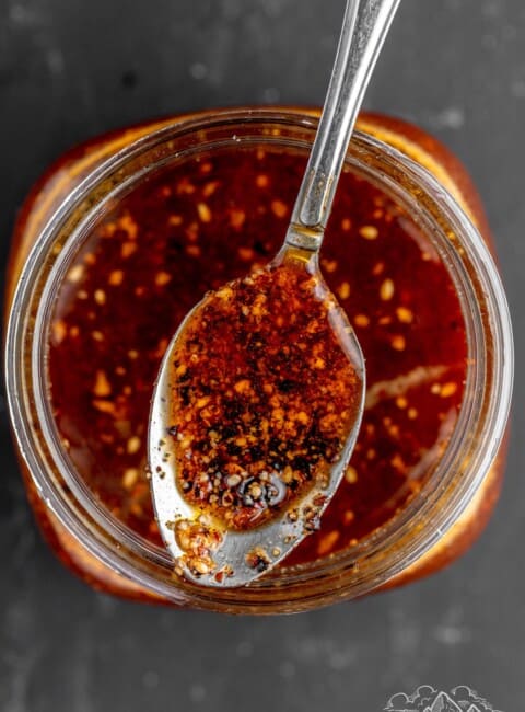 A spoon with salsa macha over a mason jar
