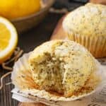 Two lemon poppyseed muffins one with a bite taken out