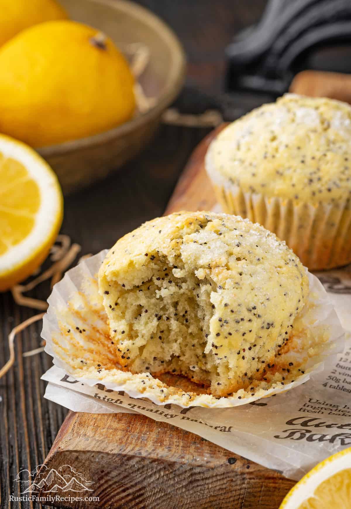 Two lemon poppyseed muffins one with a bite taken out