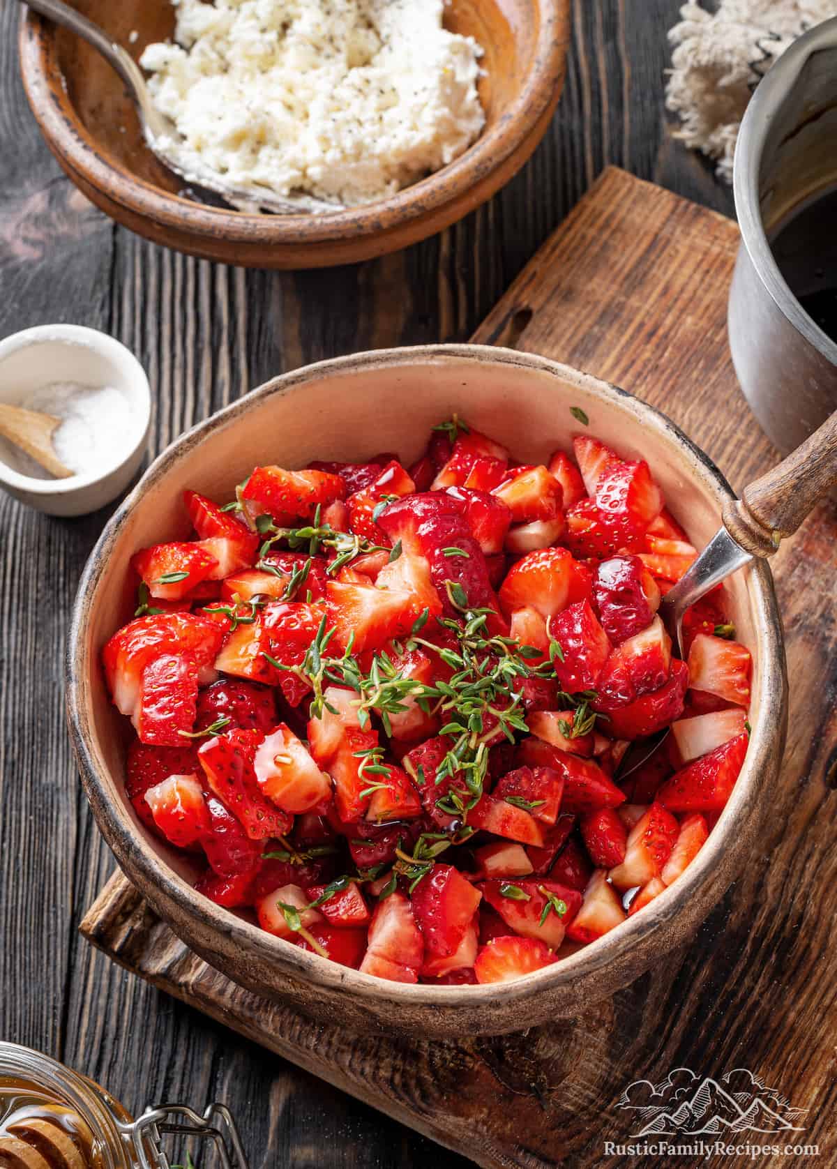 A bowl of strawberries next to a bowl of goat cheese for bruschetta