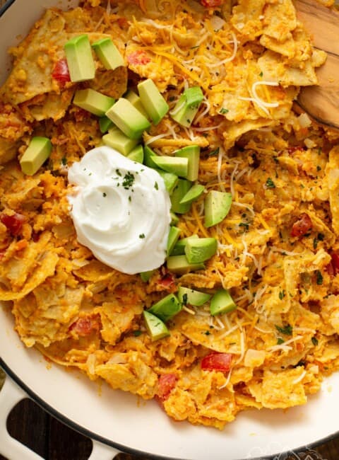 Sweet potato migas in a pan topped with avocado and sour cream