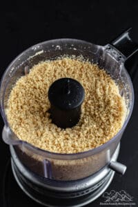 Pulverized Golden Oreo cookie crumbs in a food processor.