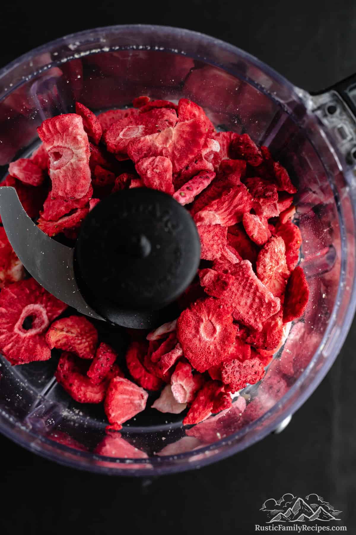 Top view of dried strawberries inside a food processor.