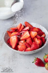 Sprinkling sugar on a bowl of strawberries