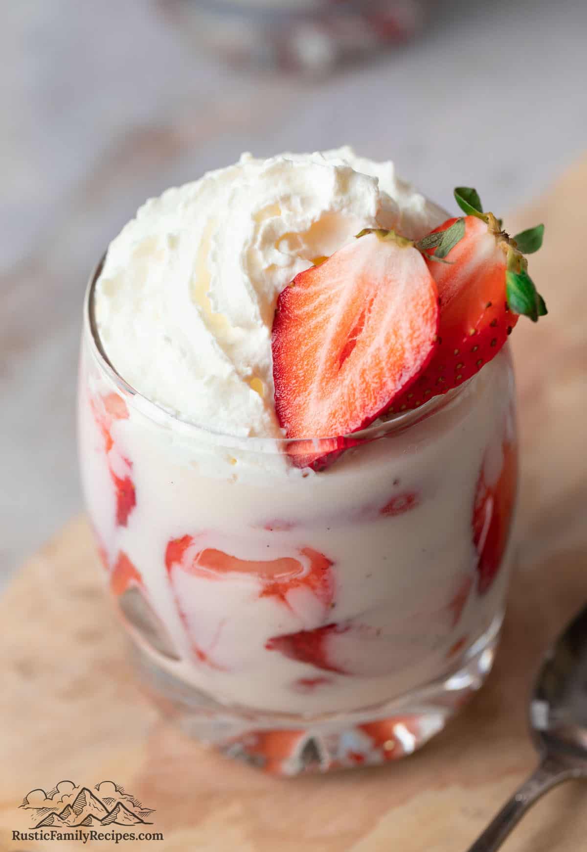 Strawberries, cream, whipped cream and a sliced berry in a glass
