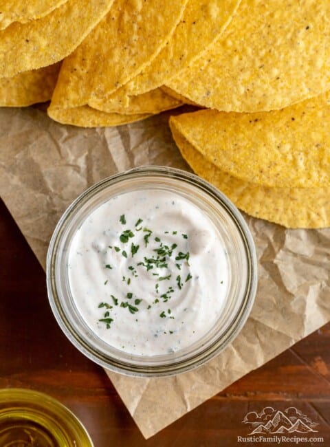 A small mason jar with taco sauce next to taco shells