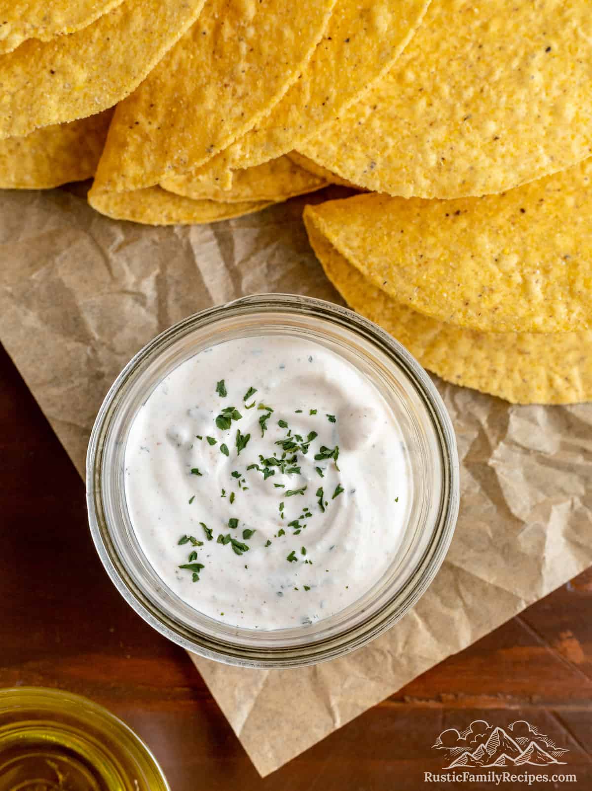 This ranch taco sauce has a spicy kick and oodles of flavor! Inspired by the Taco Bell dipping sauce, add it to tacos, burritos & flautas. A small mason jar with taco sauce next to taco shells