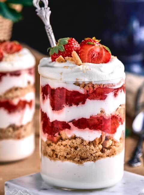 Two strawberry ice cream parfaits with a spoon in one