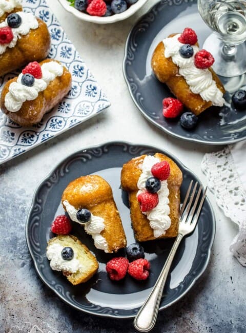Rum Babas on a plate with whipped cream and berries