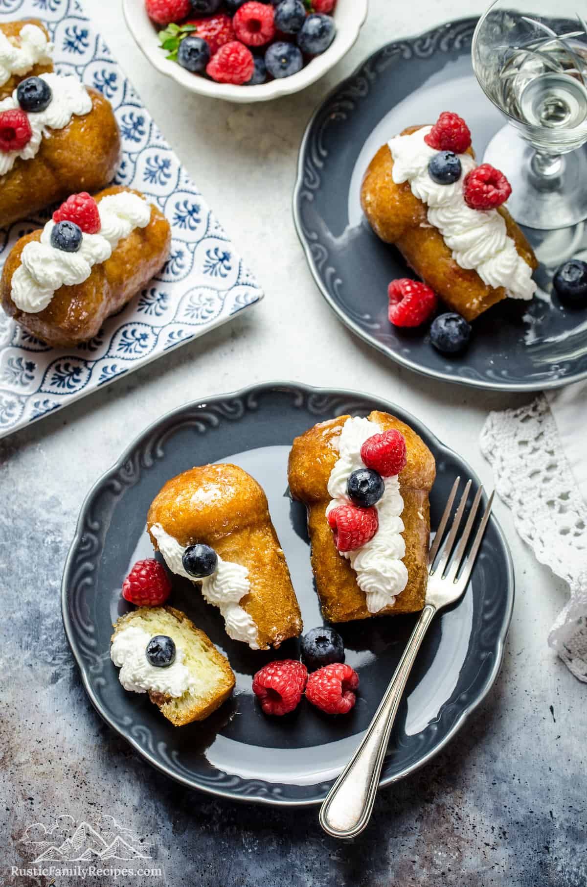 Rum Babas on a plate with whipped cream and berries