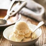 Scoops of bourbon vanilla ice cream in a bowl with a spoon.