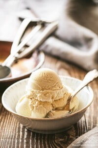 Scoops of bourbon vanilla ice cream in a bowl with a spoon.