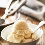 Scoops of bourbon vanilla ice cream in a bowl with a spoon.