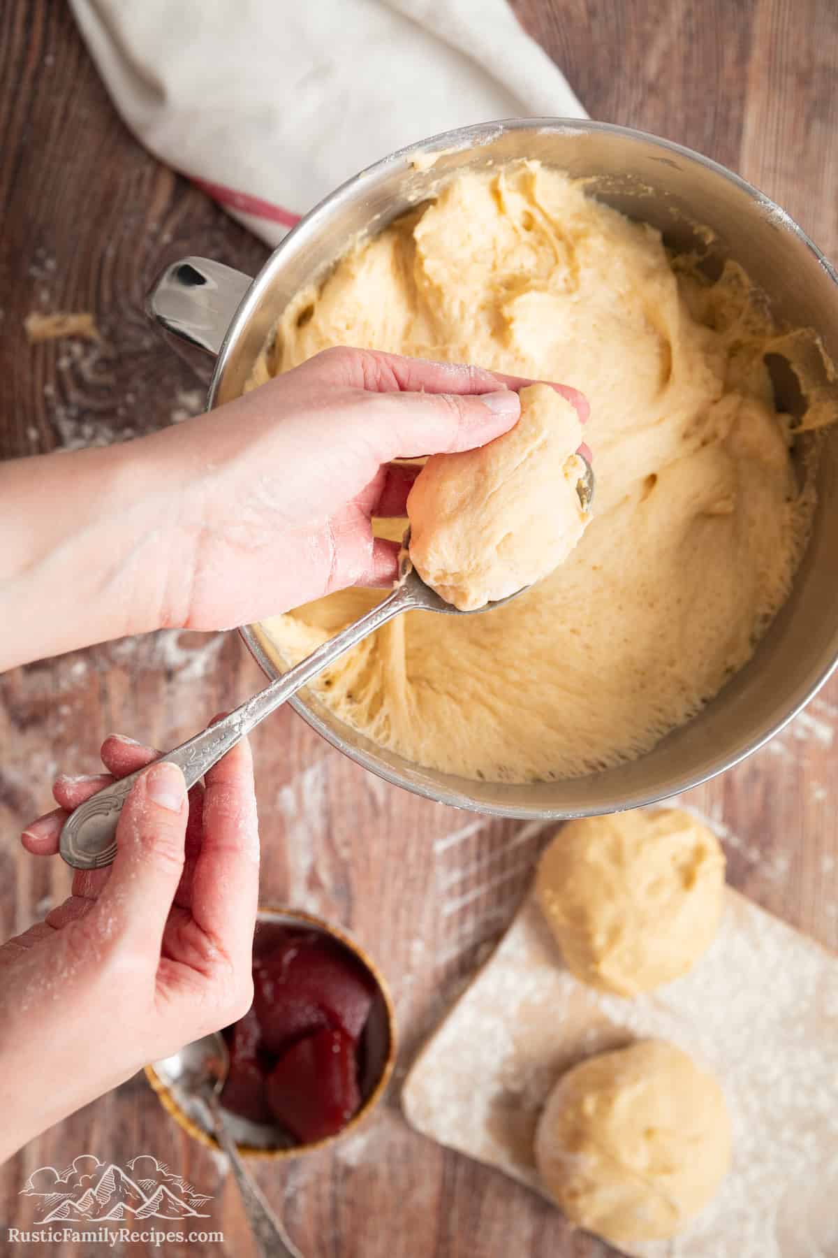 A hand shaping a spoonful of paczki dough