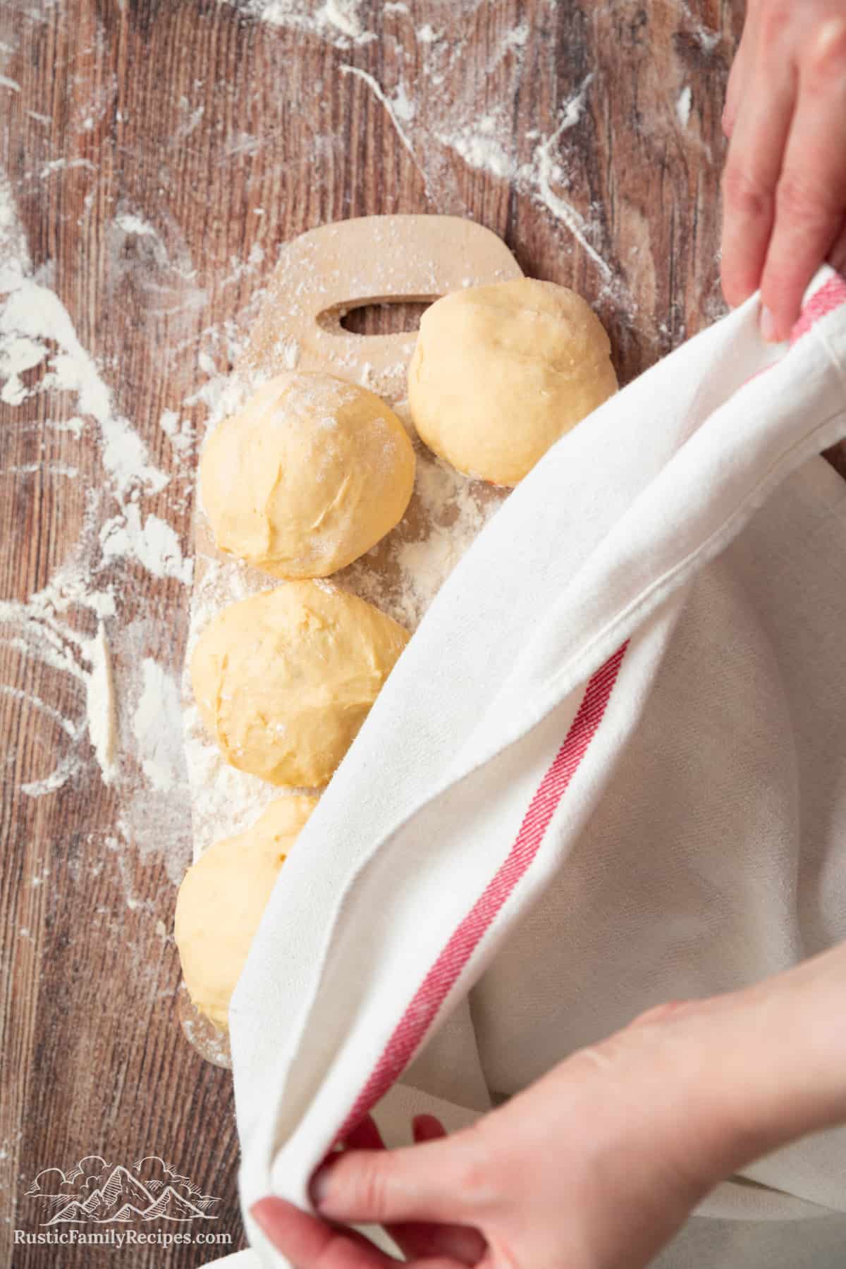A towel being placed over paczki to rise