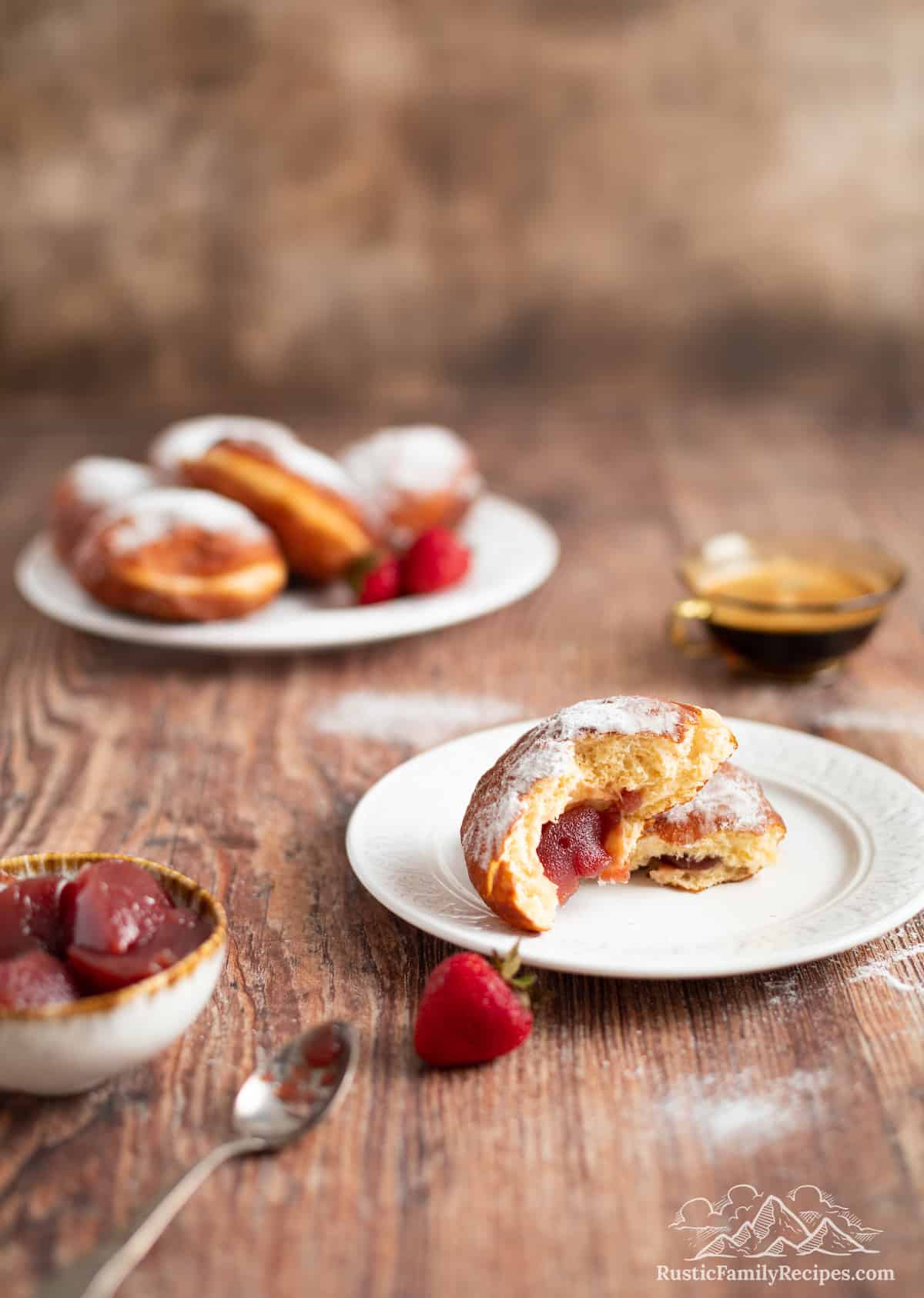 A paczki with strawberry filling on a plate cut in half