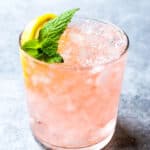 Pink cocktail in a glass with ice, mint and lemon