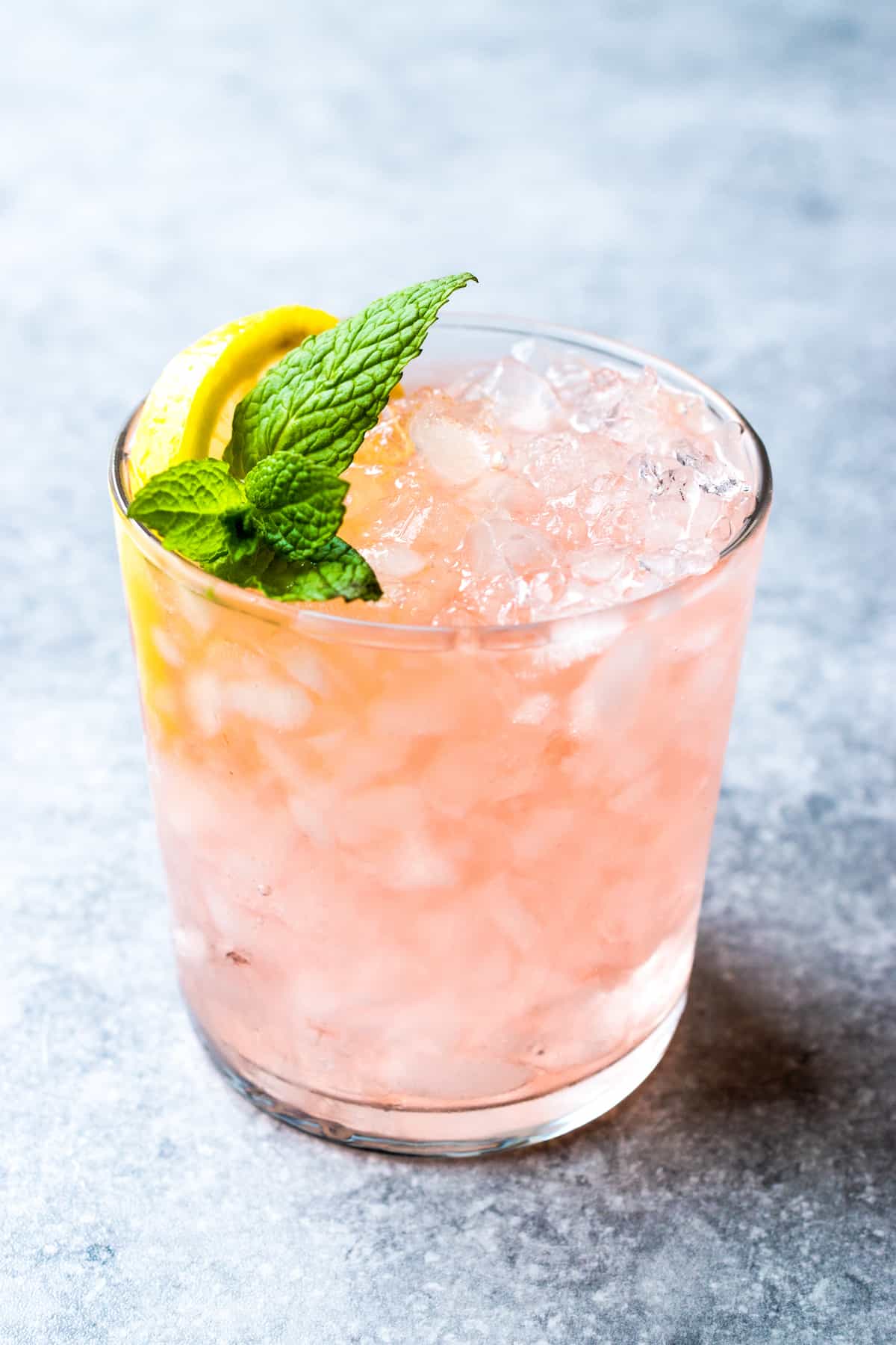 Pink cocktail in a glass with ice, mint and lemon