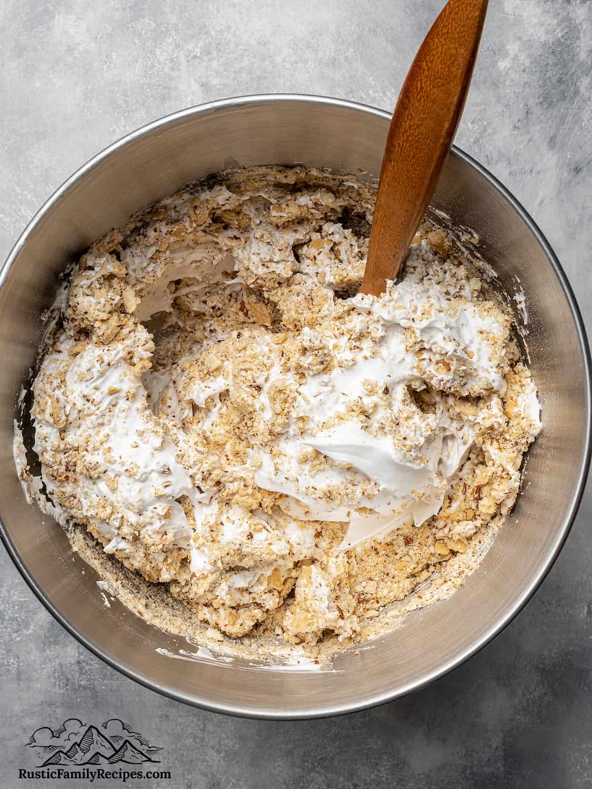 Folding crushed Maria cookies into meringue in a stand mixer bowl
