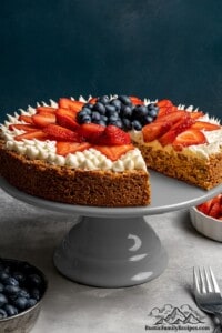 A strawberry blueberry mostachon on a cake stand