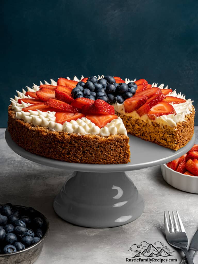 A strawberry blueberry mostachon on a cake stand