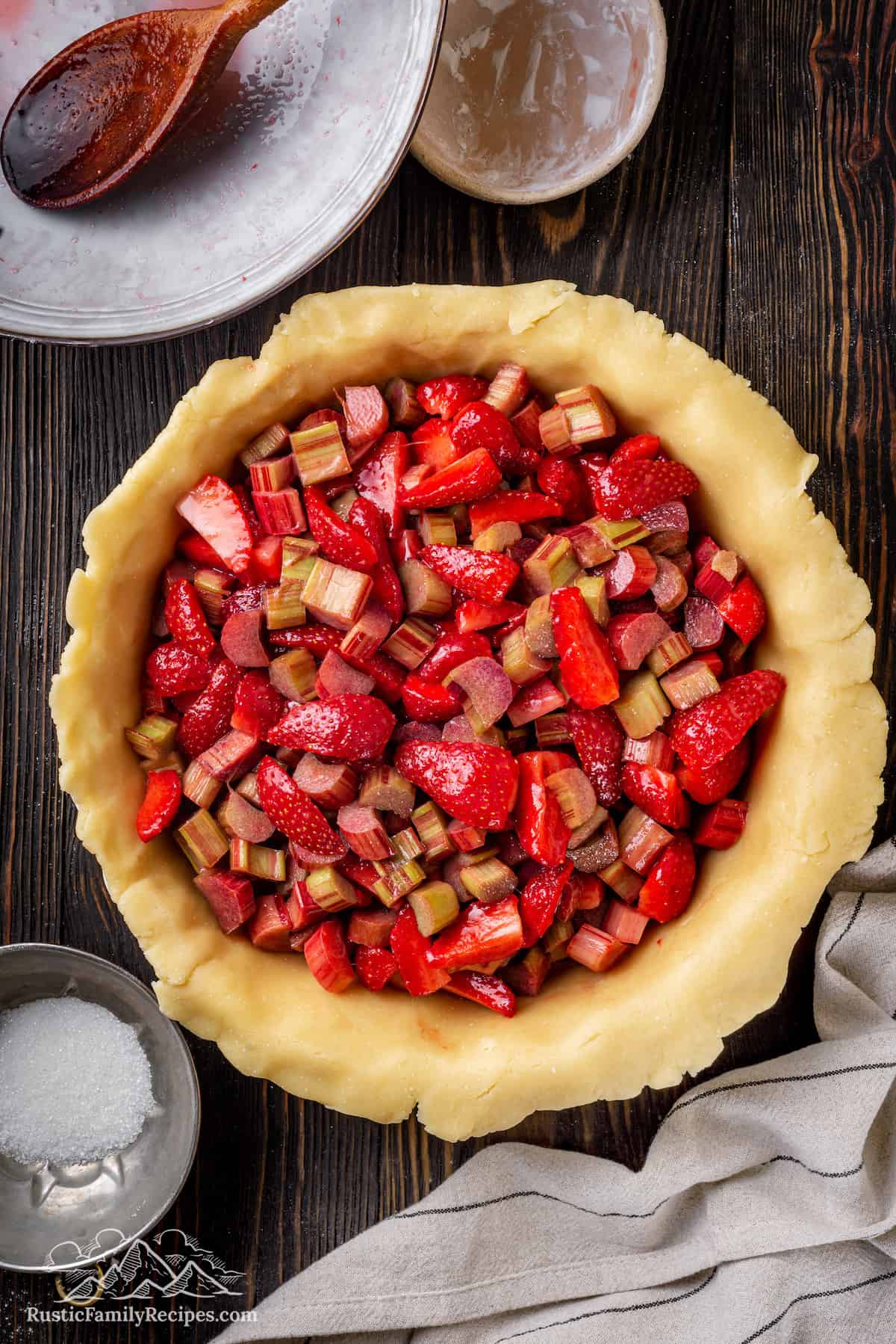 Top view of a pie pan lined with pie crust, filled with strawberry rhubarb filling.