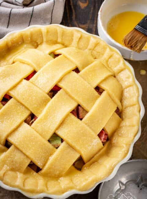 A finished, unbaked strawberry rhubarb pie with a lattice top, ready to be baked.