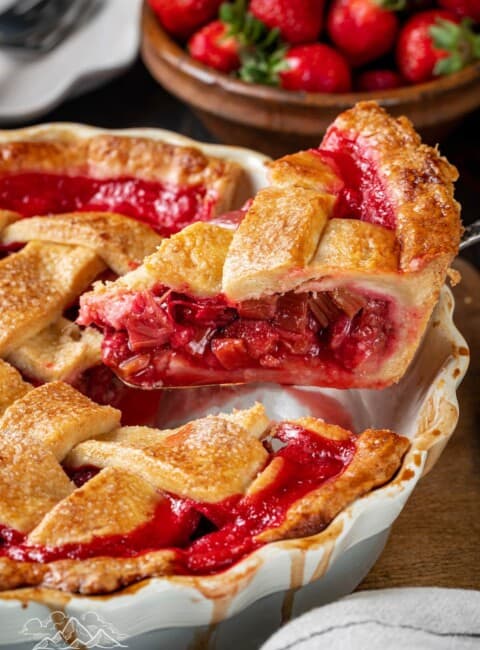A slice of strawberry rhubarb pie is lifted from a pie pan.