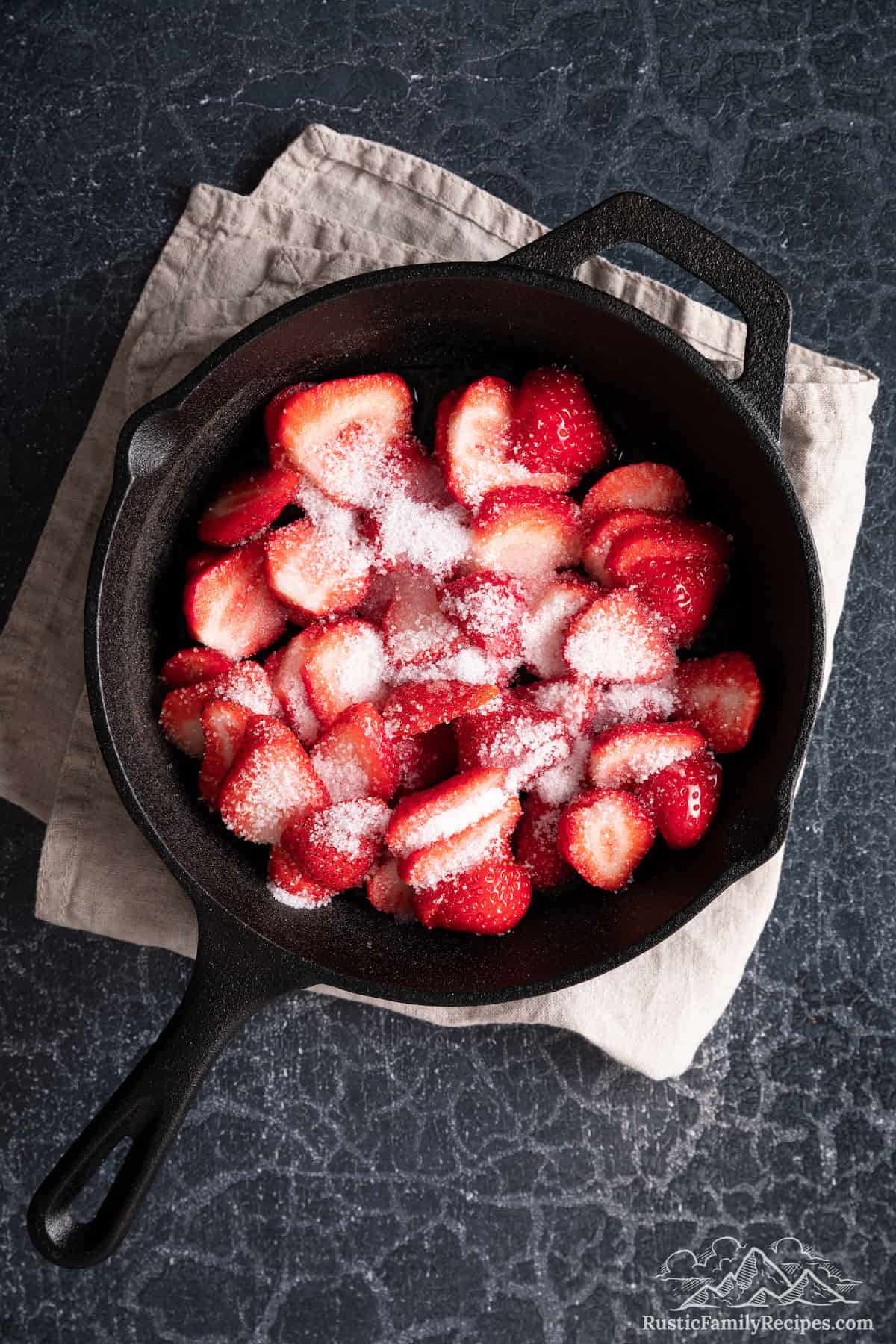 Sliced strawberries in a skillet with sugar
