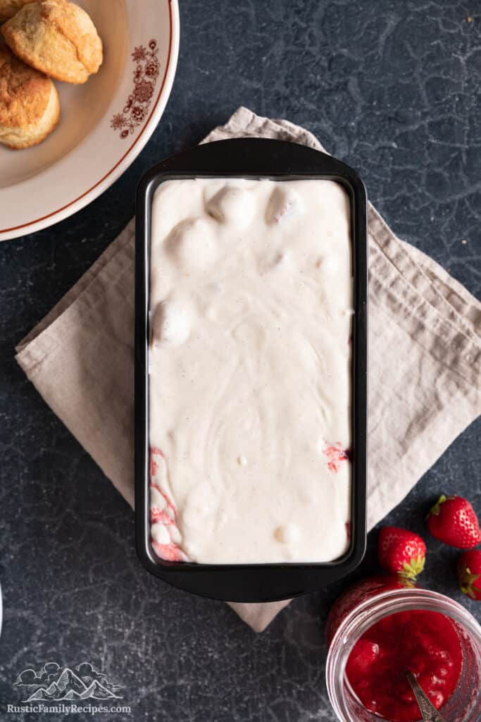Top view of strawberry shortcake ice cream base in a metal loaf pan.