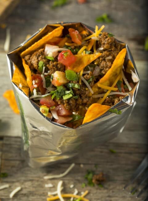 A bag filled with chips, taco meat and fixings