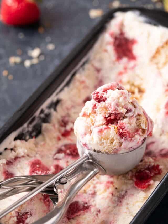 An ice cream scoops a serving of strawberry shortcake ice cream from a loaf pan.