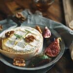Baked camembert cheese on a plate with figs and walnuts