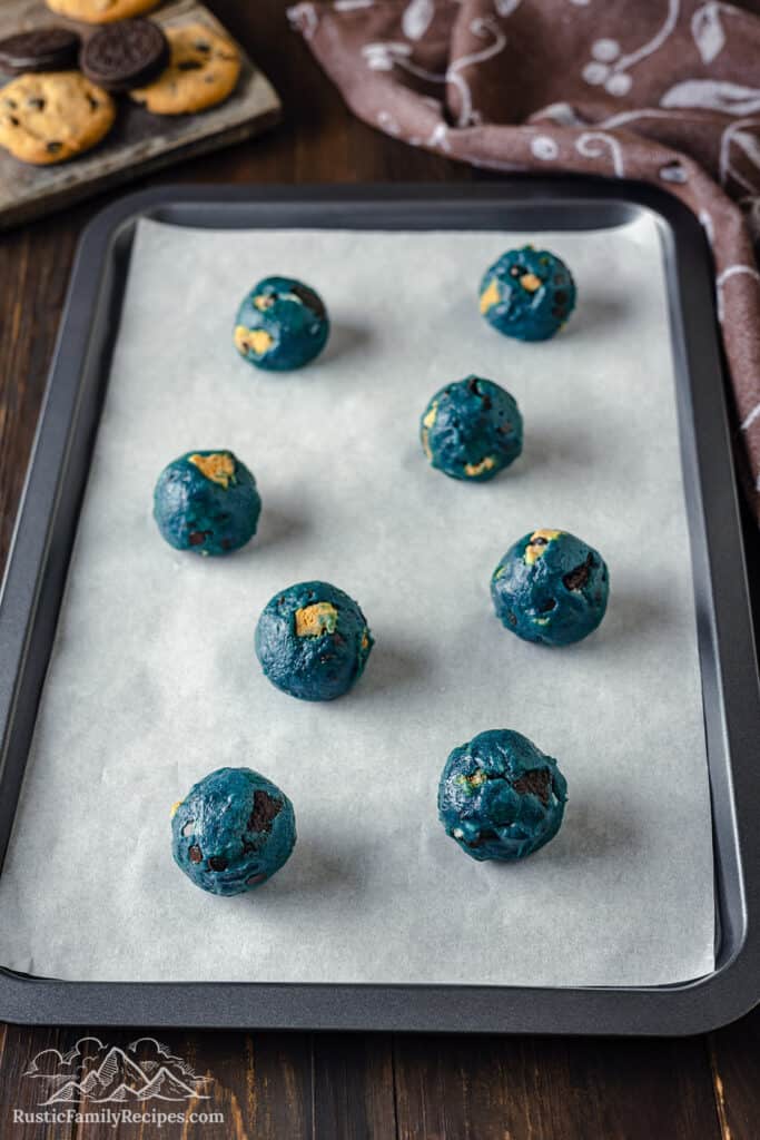 Balls of cookie dough on a baking sheet with parchment paper