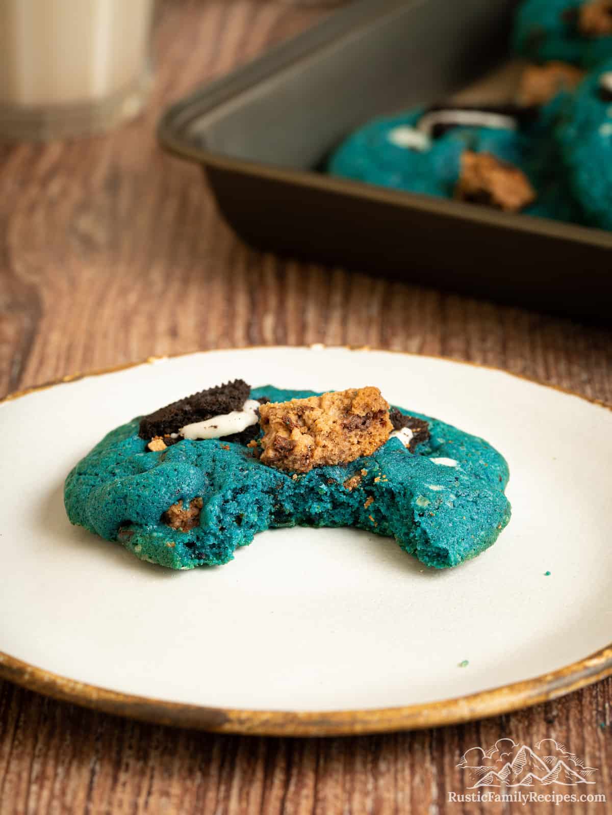 A Cookie Monster cookie on a plate with a bite missing.