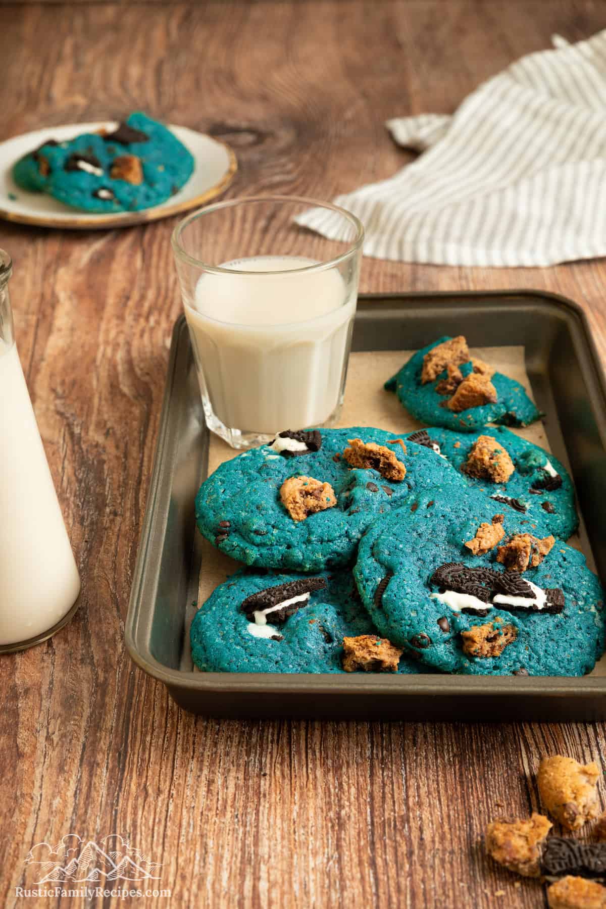 Cookie Monster cookies next to a glass of milk on a metal tray.
