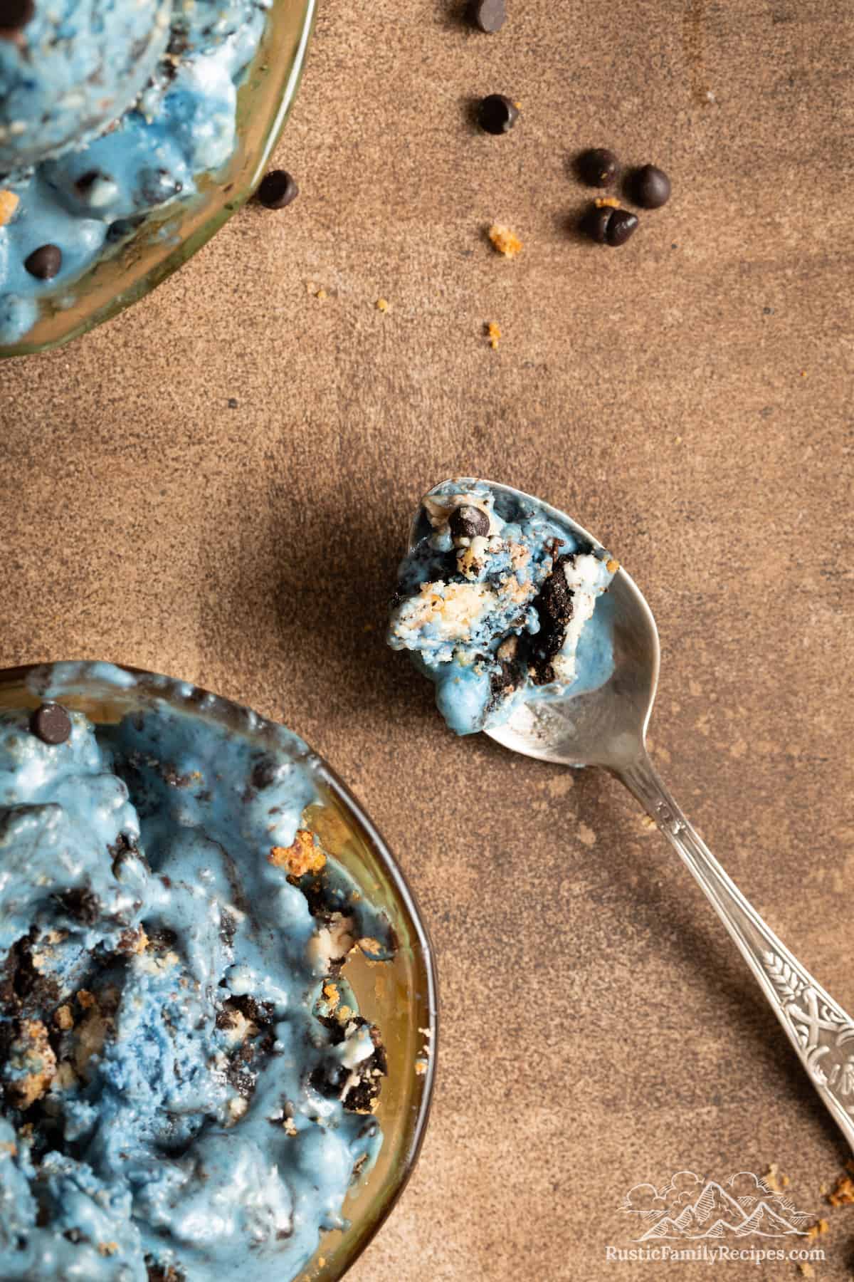 Top view of a spoonful of Cookie Monster ice cream next to a bowlful.