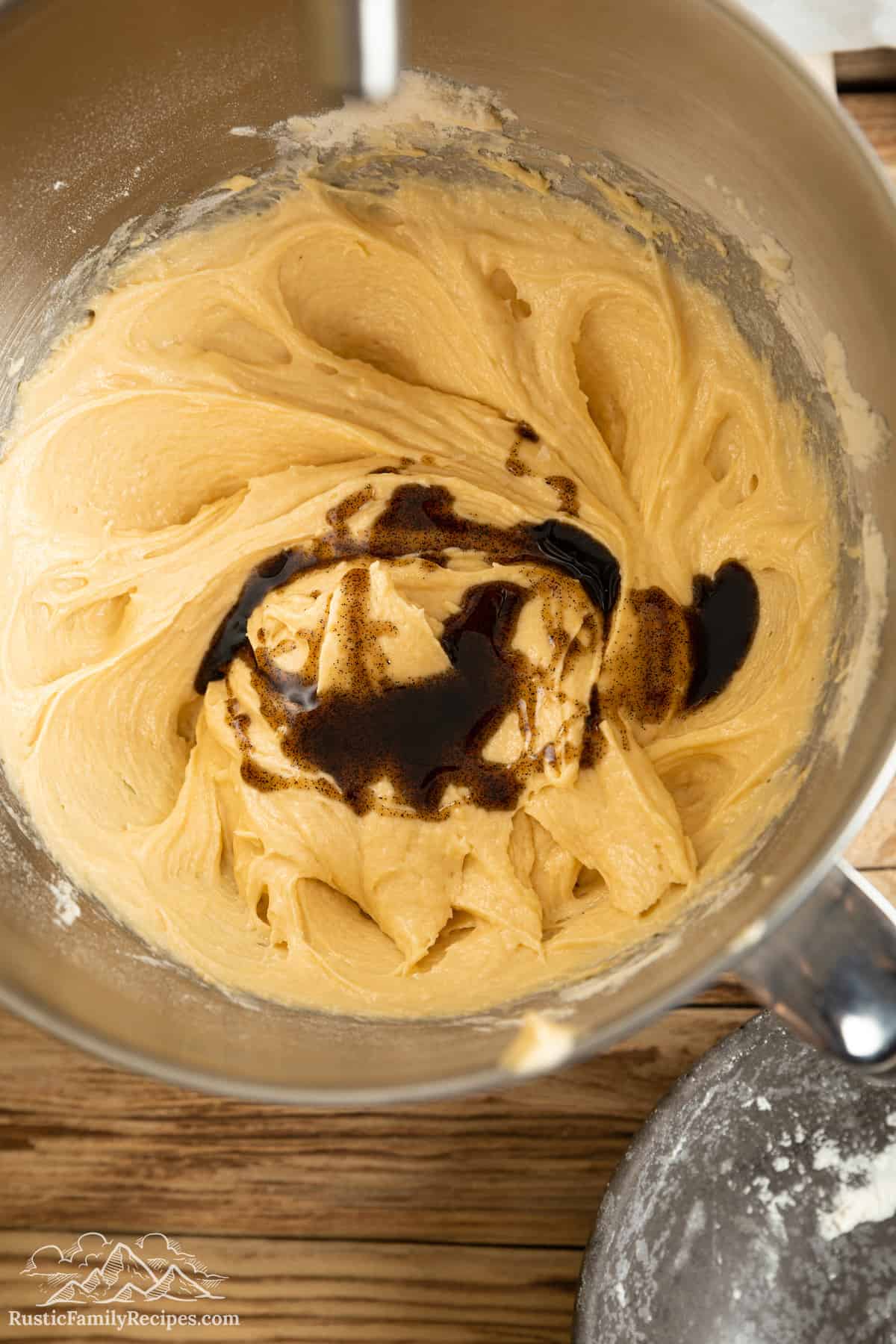 Vanilla is added into cake batter in the bowl of a stand mixer.