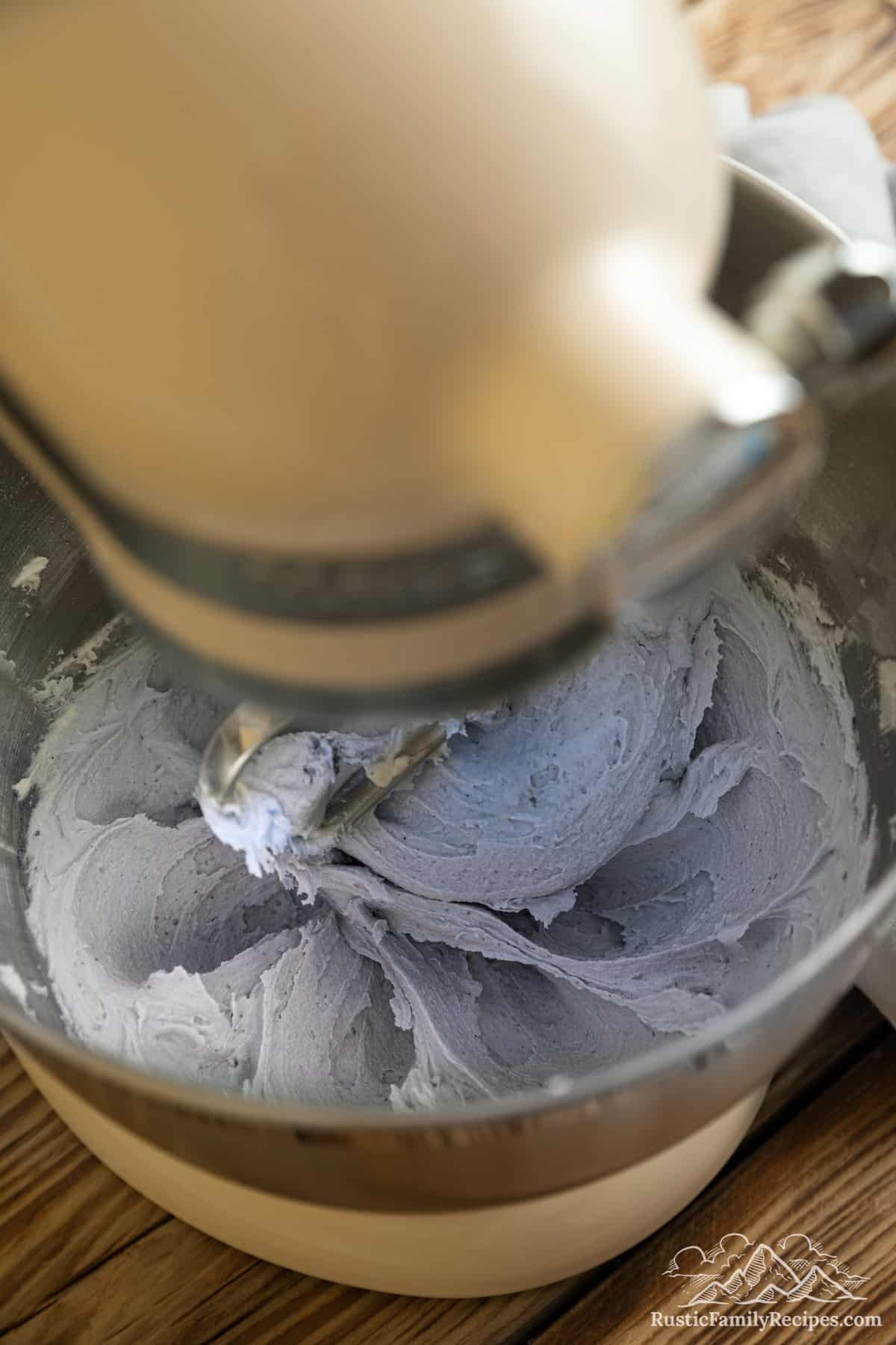Blue buttercream frosting inside the bowl of a stand mixer.