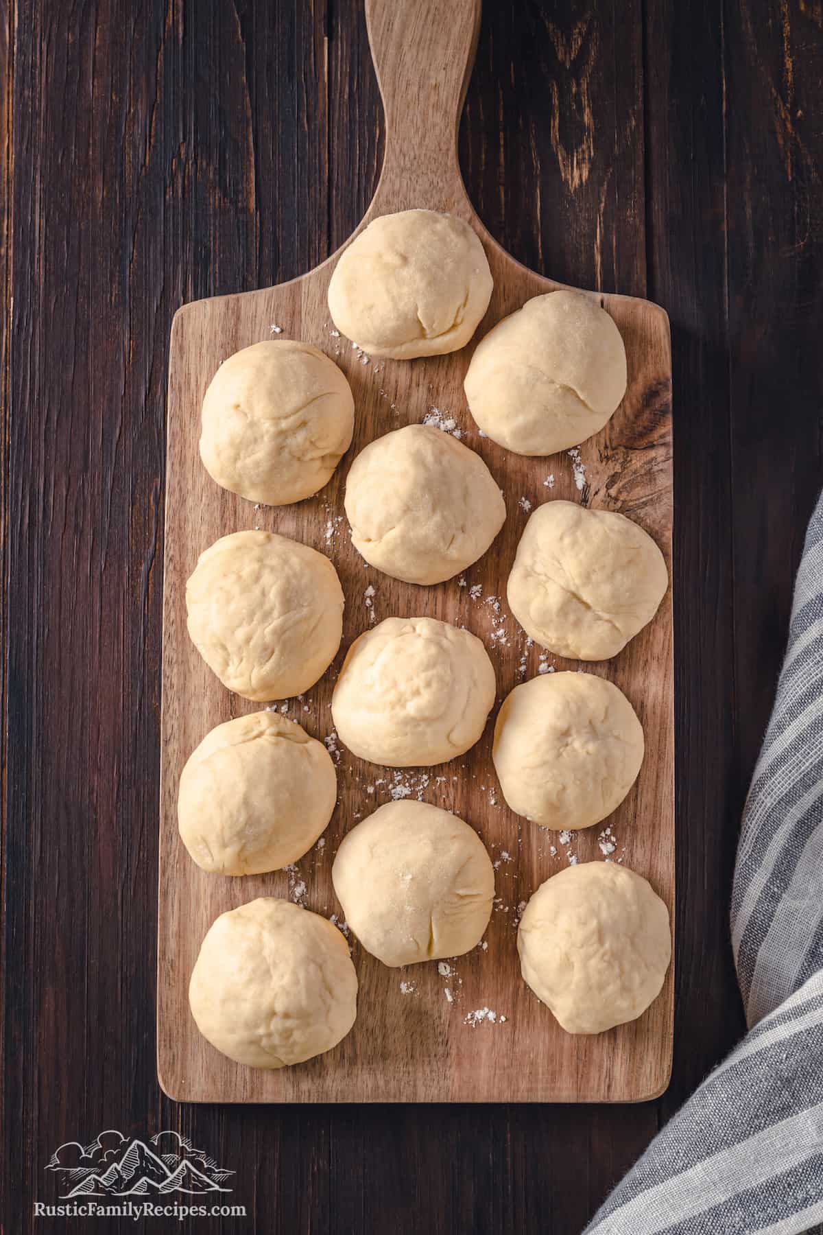 Top view of dough balls laid out on a wooden cutting board.