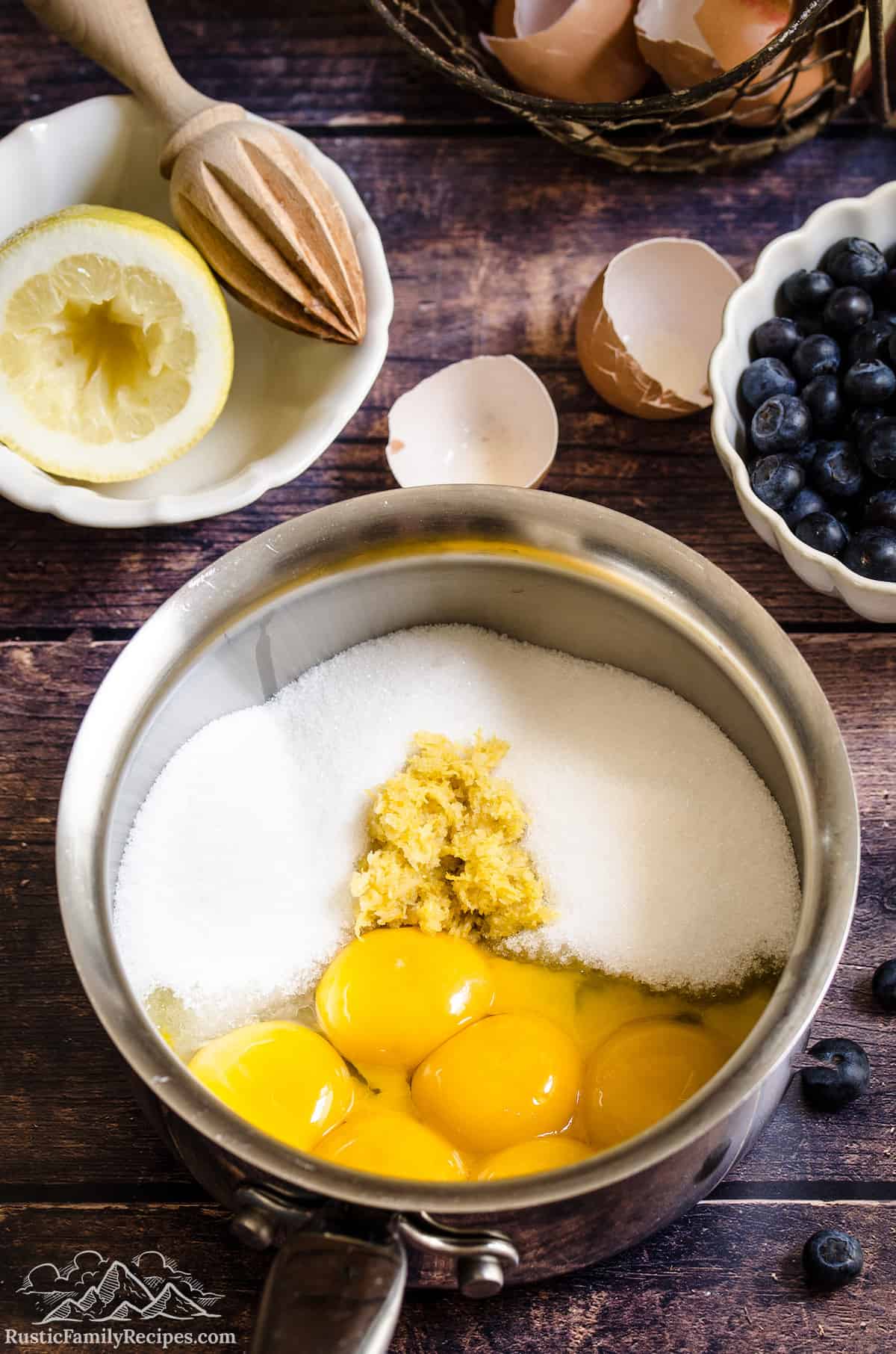Sugar, egg yolks, lemon juice, zest, and salt combined in a metal mixing bowl.