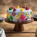 Encanto cake decorated with colorful buttercream on a cake stand.