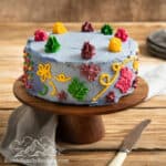 Encanto cake decorated with colorful buttercream on a cake stand.