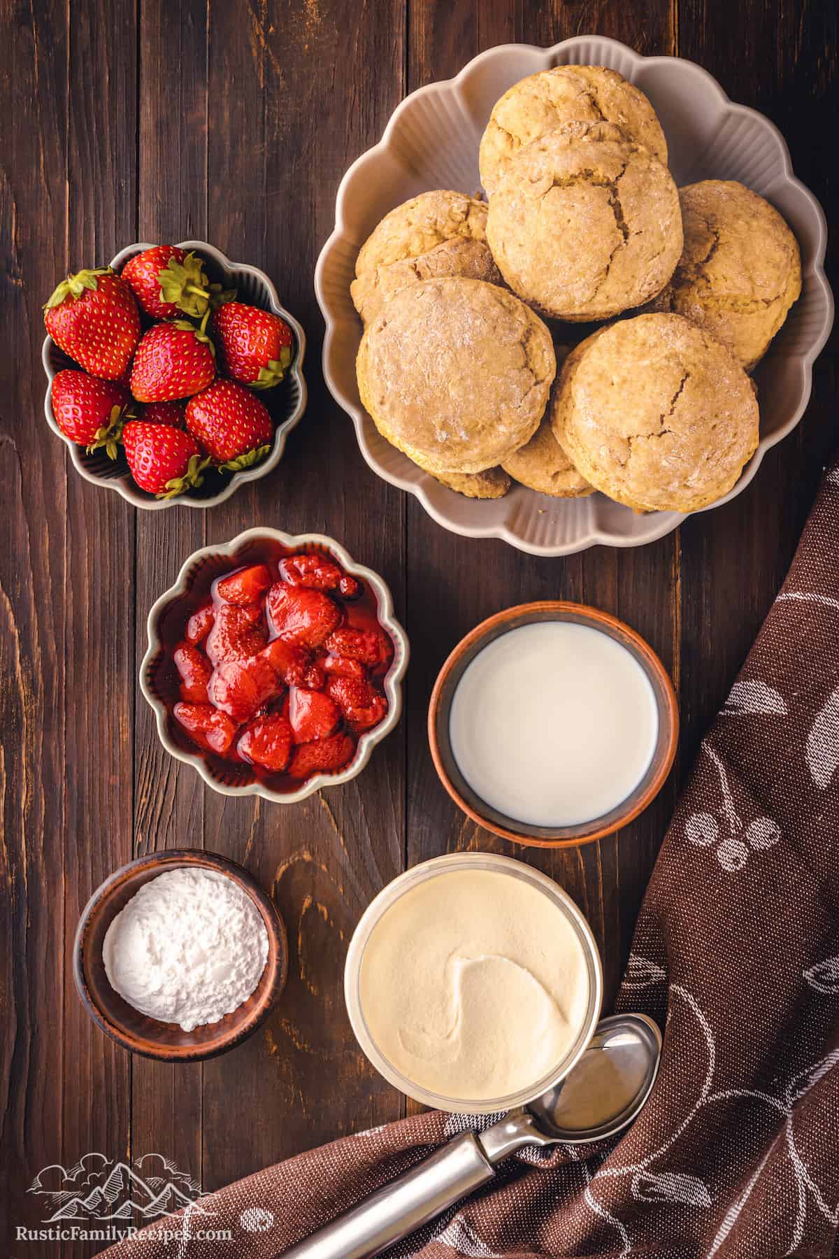 Bowls with shortcakes, strawberries, cream and strawberry sauce.