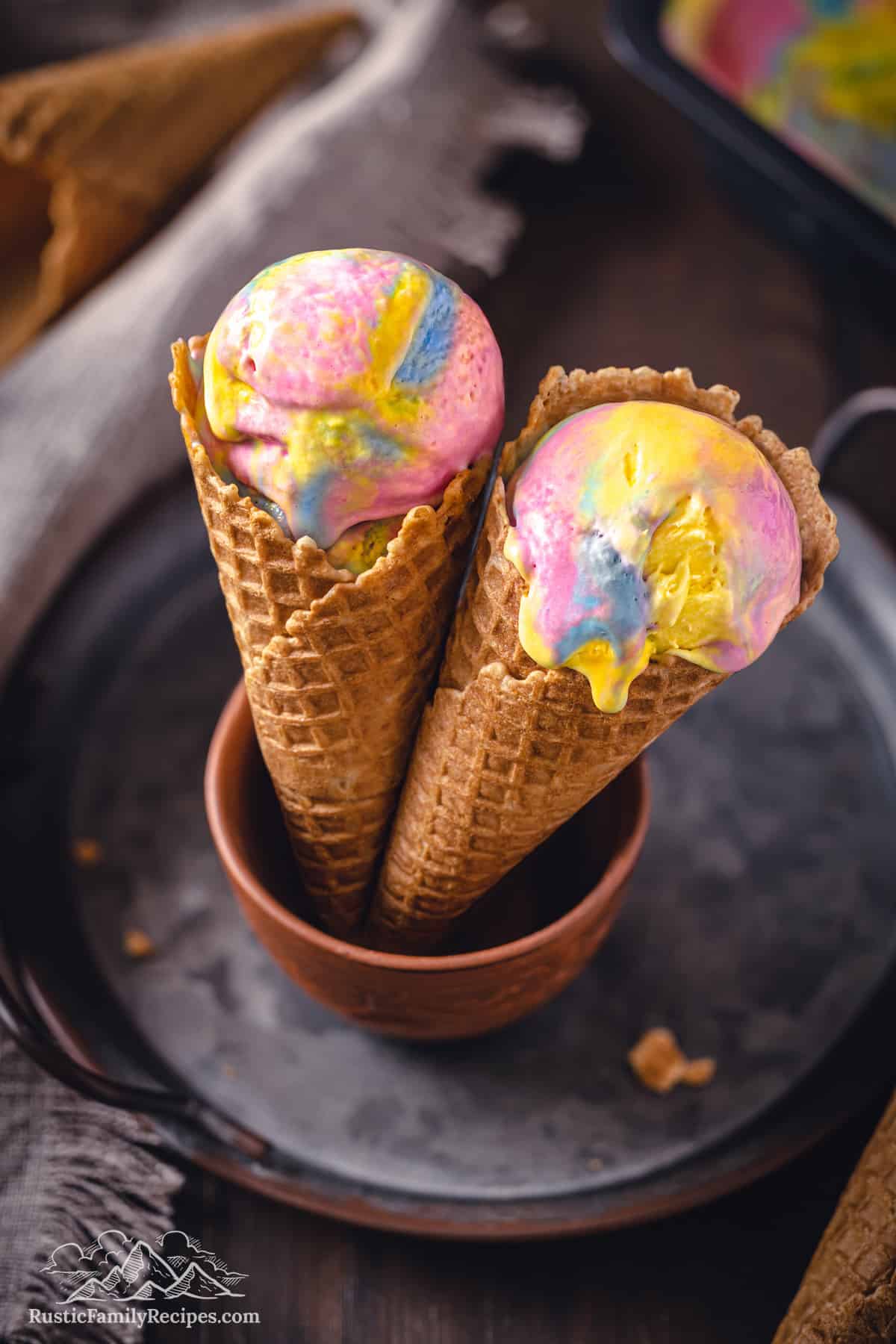 Two side-by-side ice cream cones with a scoop of Superman ice cream in each.