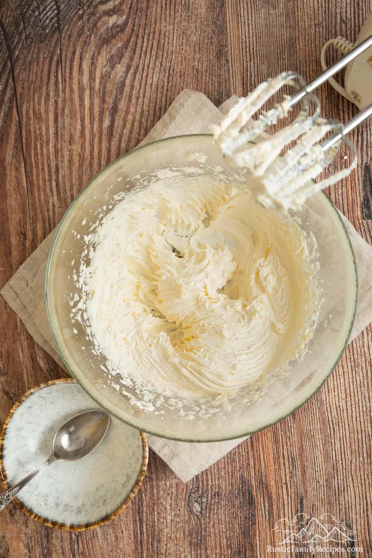 Buttercream frosting in a mixing bowl next to an electric mixer.