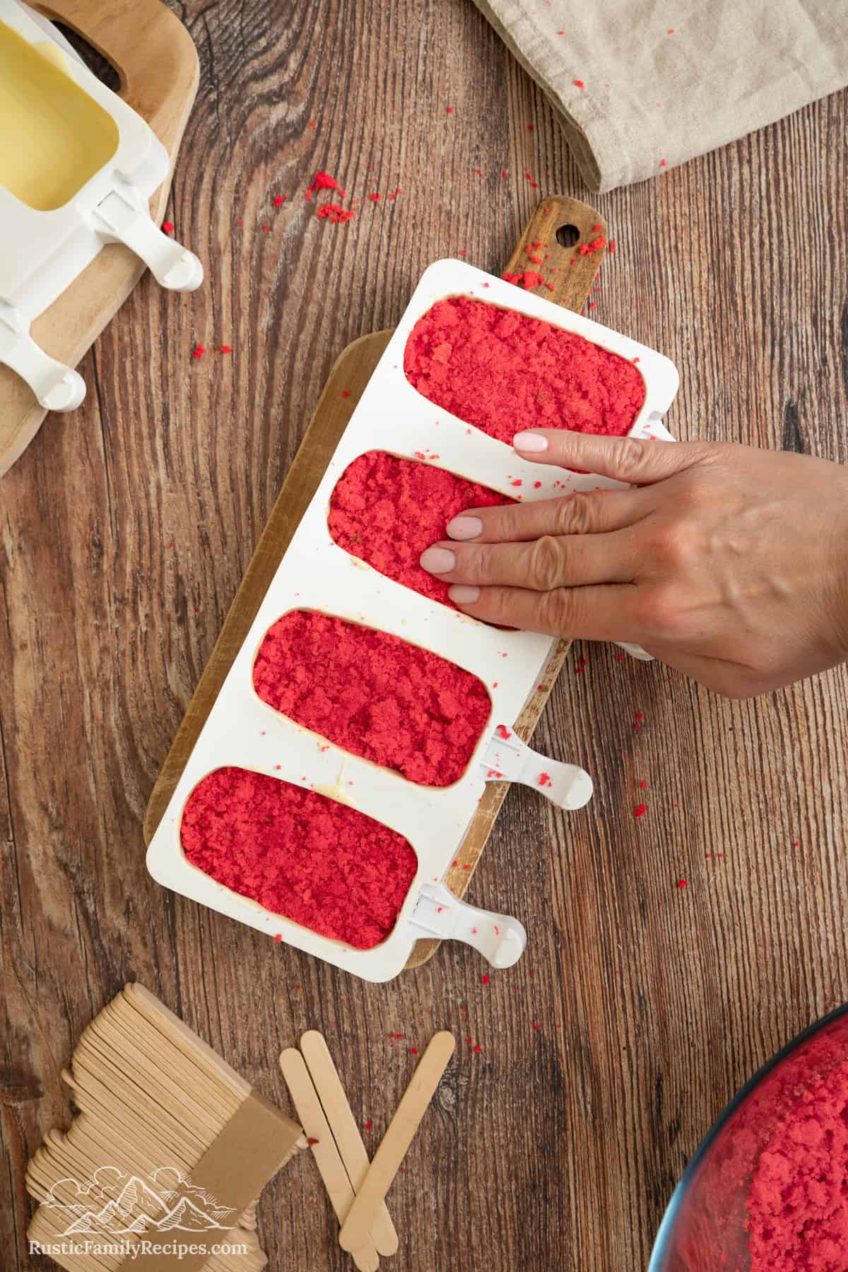Red velvet cake is pressed into cakesicle molds.