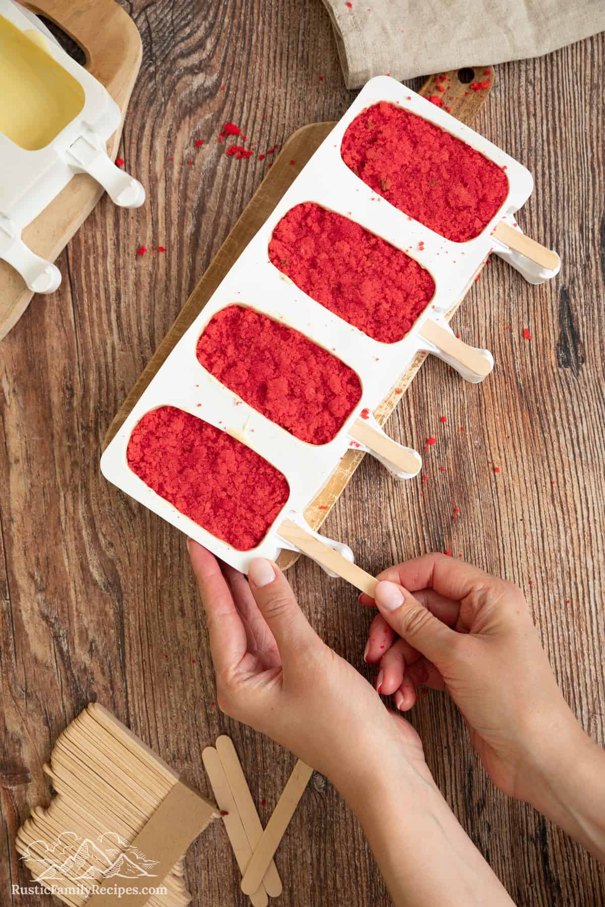 Popsicle sticks are inserted into the cakesicle molds.