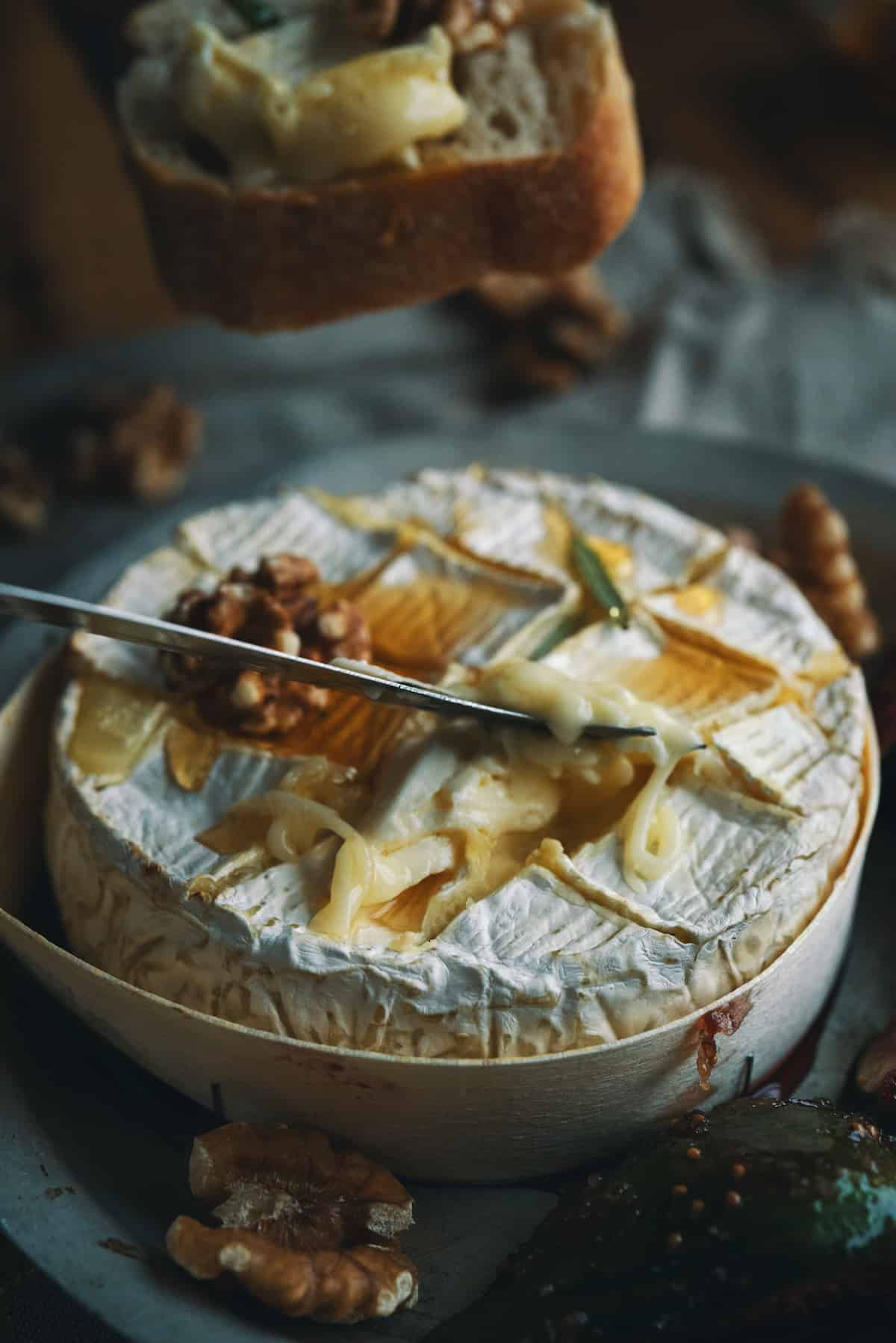 A knife scooping melted camembert cheese.